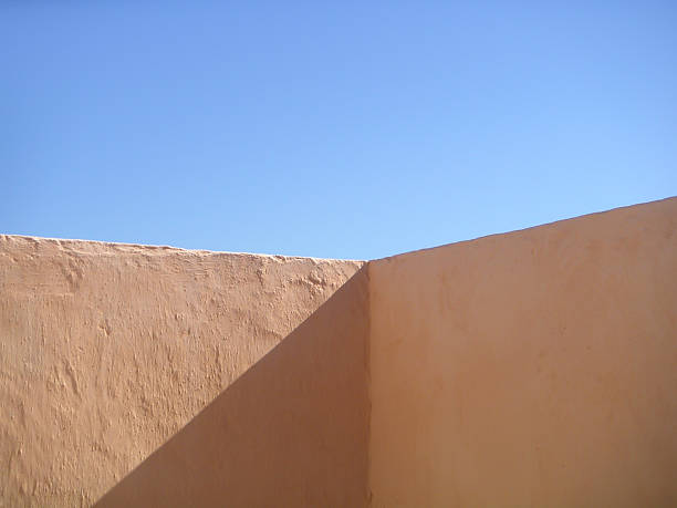 istock Warm tan walls meeting bright blue sky against simple minimalist background 2223100135