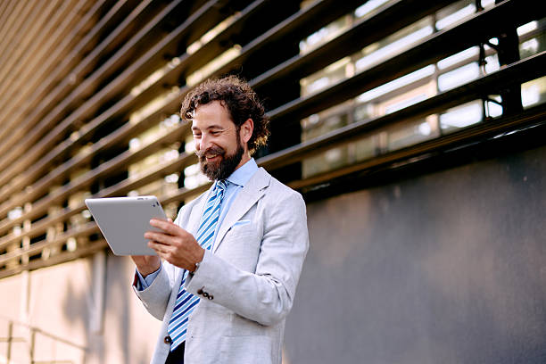 istock Smiling Businessman Using Digital Tablet in front of Modern Office Building 2223103175