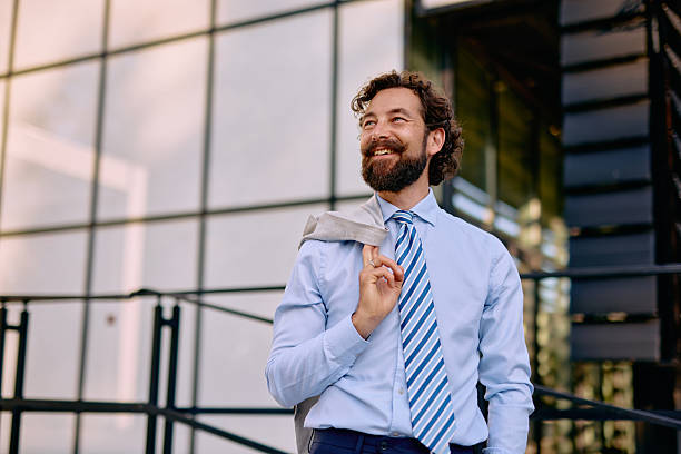 istock Smiling businessman standing outside modern office building 2223103316