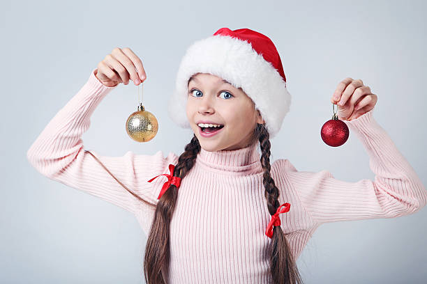 istock Young girl in santa hat with baubles on grey background 2223103805