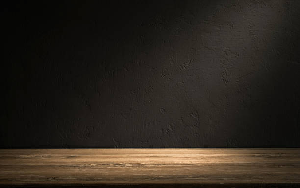 istock Empty wooden table in a dark room with textured wall background and soft lighting highlighting the surface 2223103919