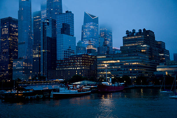Lower Manhattan skyline in dense clouds at dusk shot from the Hudson River.