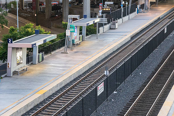 View of the empty train platforms at Anaheim’s ARTIC station in California, featuring clean modern architecture, signage for Metrolink and Amtrak, and clearly visible tracks. This image captures the structure and layout of a regional transportation hub during early morning or evening hours. Suitable for editorial use, infrastructure-related topics, or illustrating commuter rail networks in Southern California.