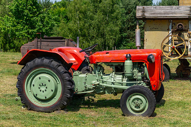 istock Classic red and green vintage tractor parked on grass, with visible engine details and large rear wheels. Surrounded by rural scenery and old agricultural machinery 2223114249