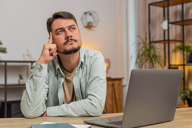 istock Caucasian Smart focused young man freelancer pensive thoughtful sitting at home office table 2223119159