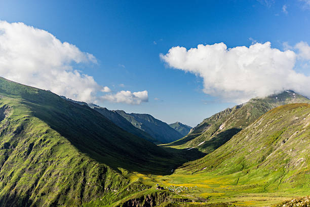 Beautiful mountain valley stretching into the distance, surrounded by verdant hills and a vibrant sky.
