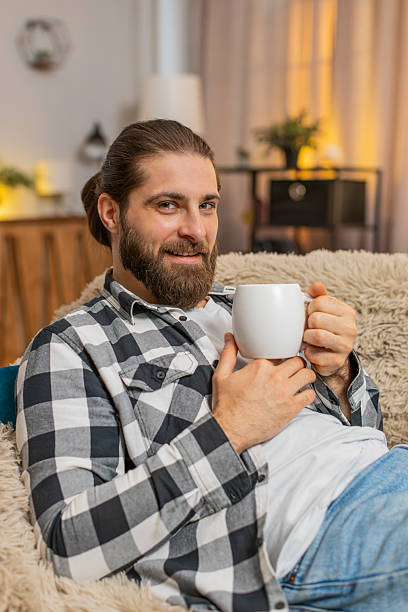 istock Young man lying with coffee mug at home, sofa calm, quiet break, easy smile, stress-free peace vibe 2223120899