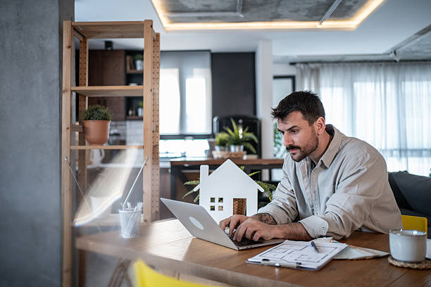 istock Architect working from home on laptop with house model on table 2223122932
