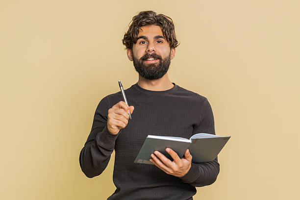 istock Thoughtful businessman making notes, writing down thoughts with pen into diary on beige background 2223123280