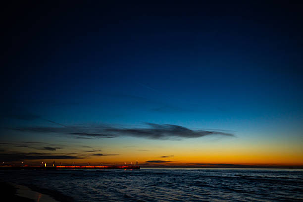 Long exposure of Atlantic Ocean in Salisbury, Massachusetts, with sky and stars during summer blue hour,