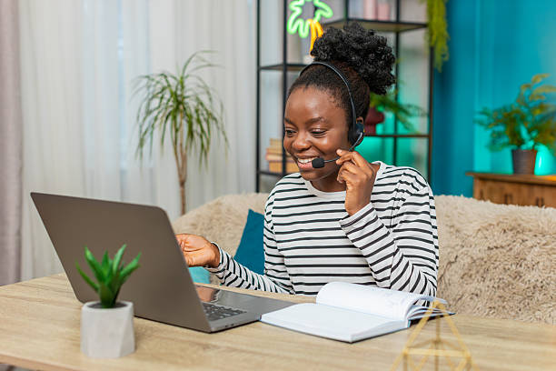 istock African American woman working call center operator headset on sofa, focused writing notes, home 2223127381