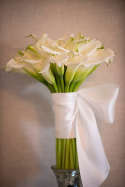Man holding many blooming white callas flowers. A bouquet of white callas lies. Beautiful bouquet of white tender callas.