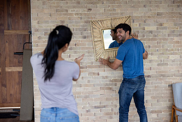 istock Happy couple hanging a mirror while decorating their house 2223144214