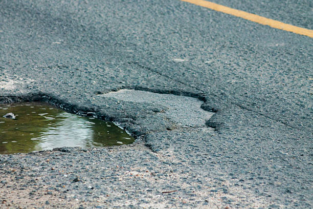 istock Old asphalt road with dangerously damaged asphalt that has potholes dangerous for the transit of motor vehicles 2223144478