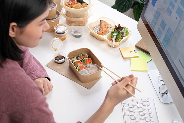 Asian woman eating healthy meal while working