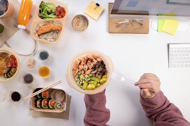 Asian woman eating healthy meal while working, Top view