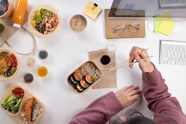 Asian woman eating healthy meal while working, Top view