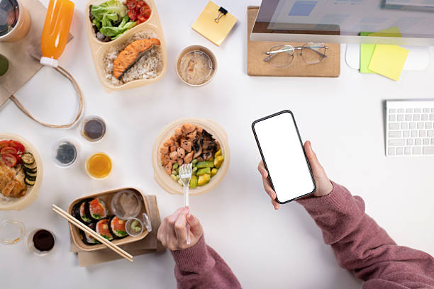 istock Asian woman eating healthy meal while working, Phone with blank white screen for copy space 2223148230