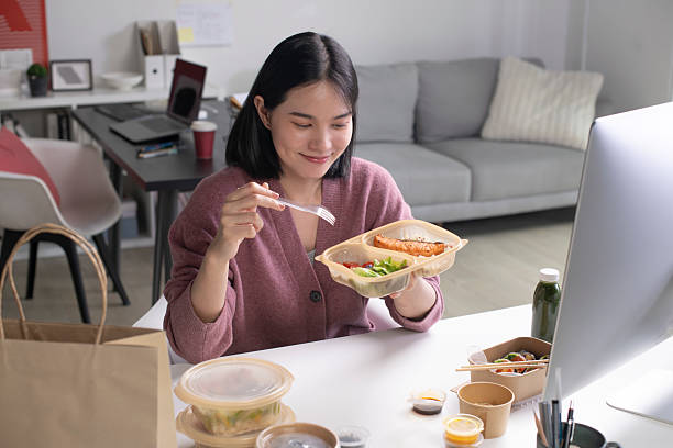 istock Asian woman eating healthy meal while working 2223148232