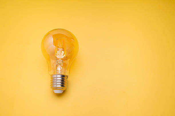 istock Clear incandescent light bulb on yellow background symbolizing innovation, energy, and ideas. 2223151194
