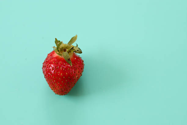 istock A single fresh, bright red strawberry with a green stem is placed on a clean turquoise background. This minimalist image emphasizes the simplicity, freshness, and natural beauty of the berry, ideal for design or healthy food advertising. 2223151628