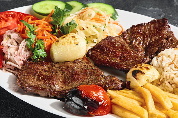 istock Beef steaks with grilled vegetables, fries and rice, bright rustic overhead plating 2223153265