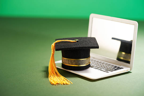 istock small mortarboard on the miniature laptop againnst green background 2223155337