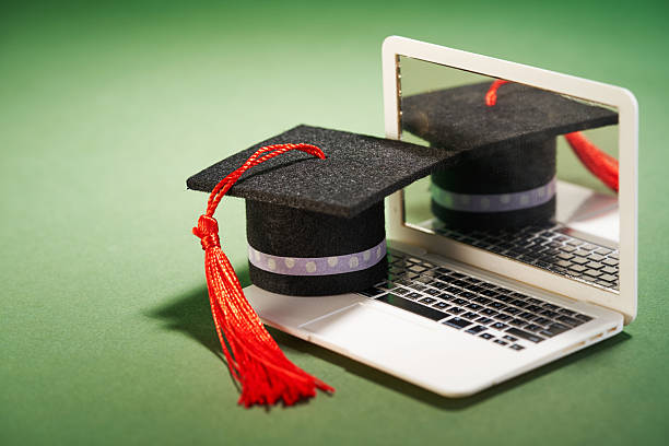 istock small mortarboard on the miniature laptop  againnst green background 2223155345
