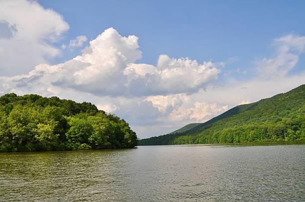 istock Serene river landscape with lush green hills and a partly cloudy sky, evoking tranquility 2223155388