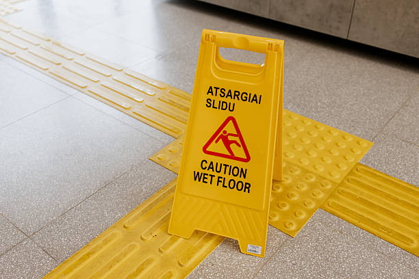 istock Yellow plastic caution sign on tactile paving for visually impaired, warning about wet floor in a public indoor space, bilingual text in Lithuanian and English 2223161627