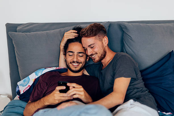 istock Gay couple relaxing in bed and using smartphone 2223162971