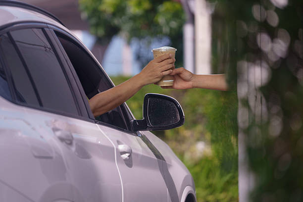 istock Customers receive coffee cups from drive-thru counter staff during rush hour. 2223163364