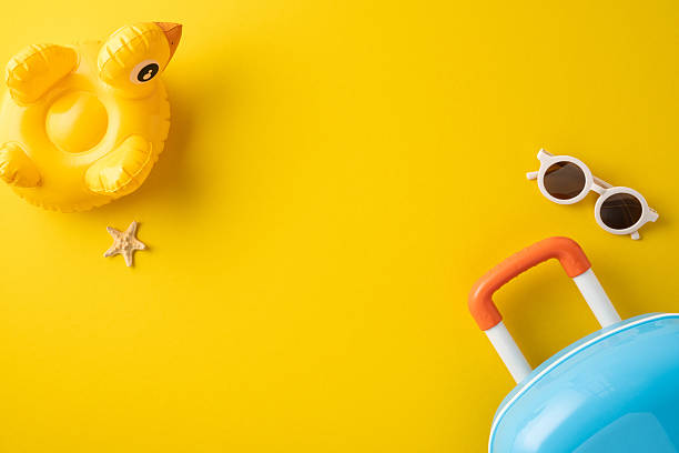 istock Vivid yellow background featuring summer travel items including a suitcase, sunglasses, inflatable float and a starfish to evoke relaxation and vacations 2223168065