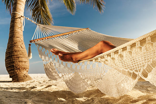 Unrecognizable woman's legs during serene moment on a hammock at the beach. Copy space.