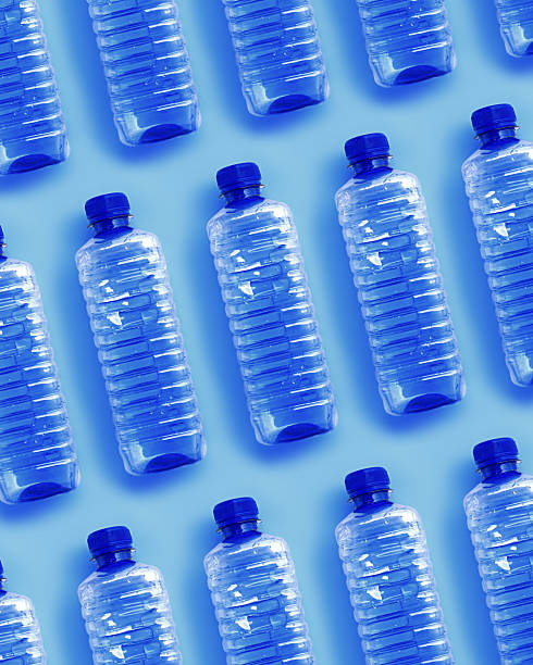istock Clear single-use plastic water bottles for water on light blue background close-up geometric pattern, minimal style object, top view row bottle, Pollution, environmental protection, plastic waste 2223170021