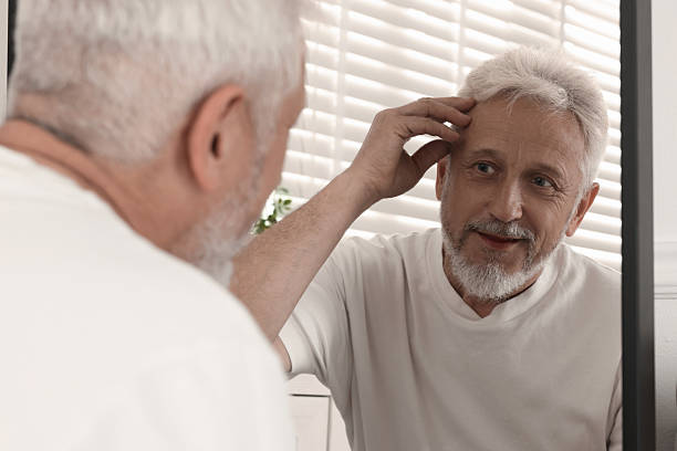 istock Senior man looking in mirror at home 2223173929