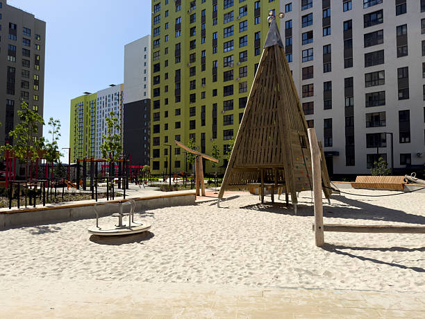 Eco friendly urban playground with wood structures and sand base promotes creative outdoor play for children, set in modern residential courtyard surrounded by high rise buildings