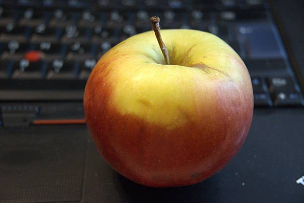 istock Healthy snack in work. One whole apple fruit with computer. 2223178999