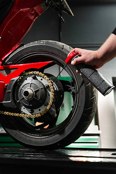 istock Motorcycle Chain Lubrication with Oil. Oiling motorcycle chain helps reduce wear, prevent rust, and ensure clean drivetrain for top riding performance. Clean oil spray is applied to motorcycle chain. 2223183888