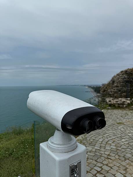 istock Binocular viewer facing the sea, installed on a coastal platform with stone pavement and glass railing. Image fits travel, tourism, education, and infrastructure use. 2223184889