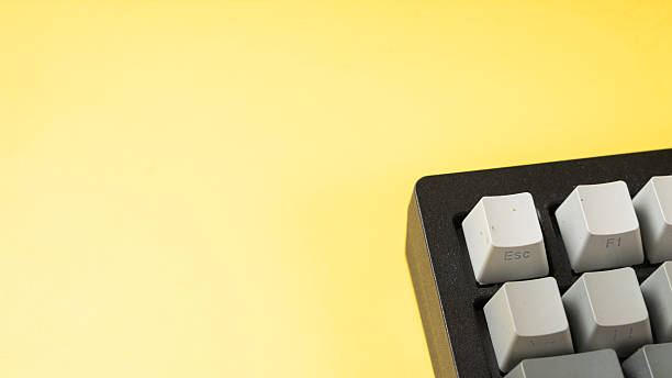 istock Minimalist mechanical keyboard with gradient gray keycaps placed on a vibrant yellow background, showcasing a clean, modern, and top-down tech aesthetic 2223186776