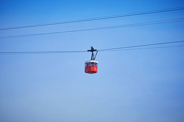Red cable car cabin hanging in the sky, part of Barcelona's Port Aerial Tramway on a clear sunny day