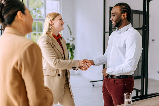 istock Two young colleagues shaking hands during meeting at modern office 2223189220