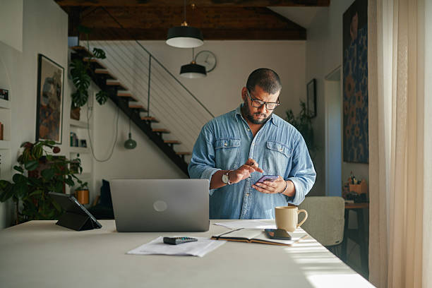 istock Professional young man wearing glasses using smartphone while working in a contemporary home office 2223189403