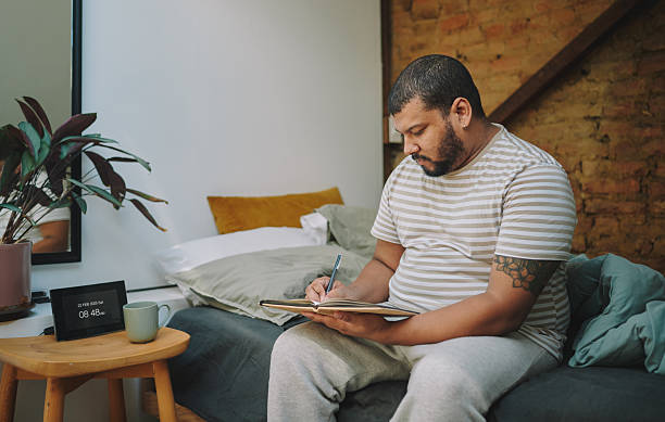 istock Man writing his morning pages in a notebook while sitting in cozy bedroom 2223190558