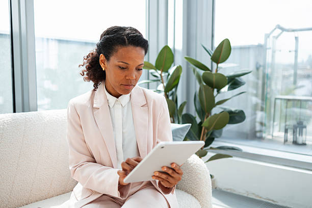 istock Professional woman seated on sofa working with a tablet in modern setting 2223190685