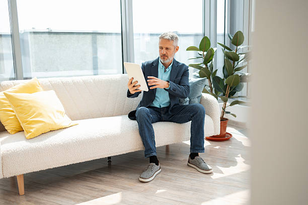 istock Man sitting on sofa using digital tablet in a modern living room 2223190704