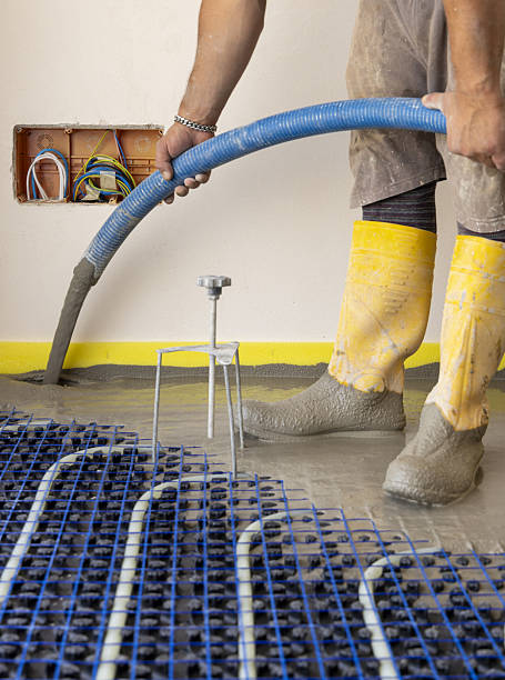 istock Man pouring concrete over floor heating installation in a new building. Modern construction system 2223190818