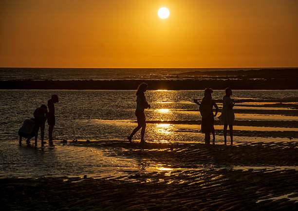 Tarifa, Cadiz, Spain.  June 27, 2025. Group of bathers enjoying the sunset on the beach of Tarifa.