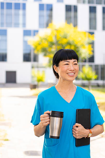 istock Female Nurse Using Tablet Outside Hospital on a Coffee Break 2223193579